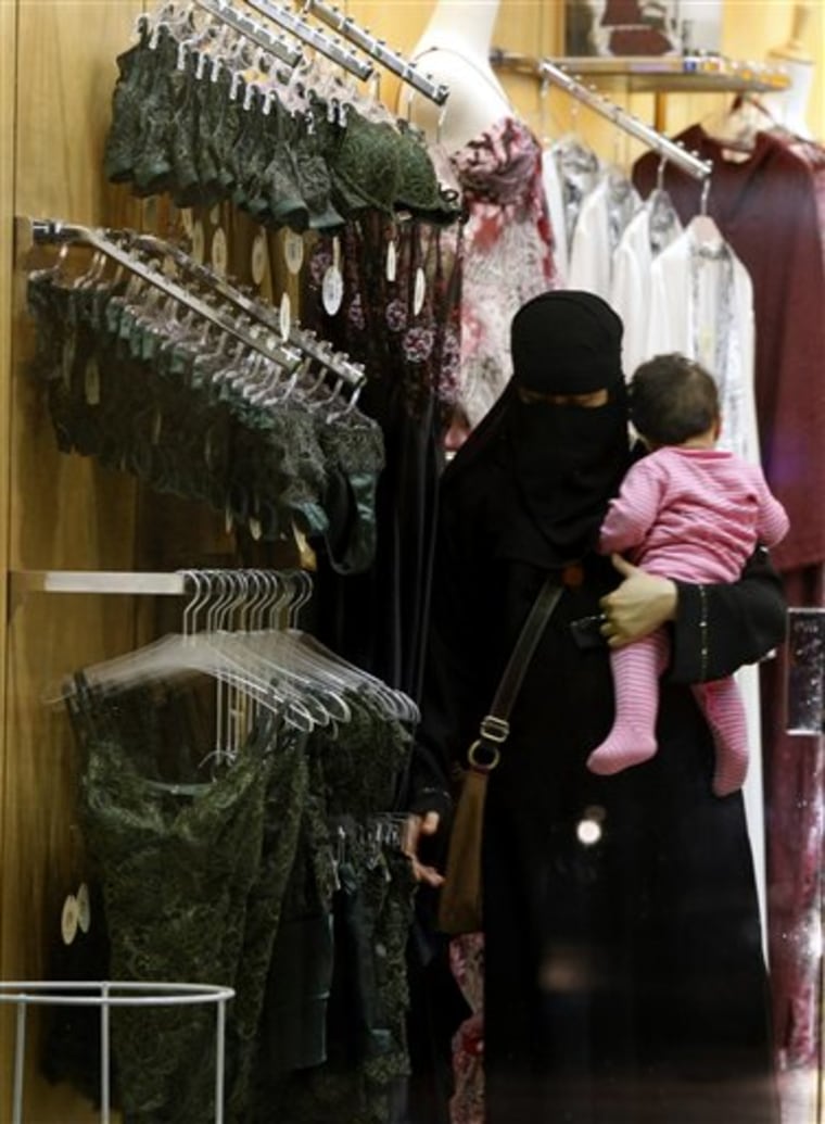 A Saudi woman holding a child checks out lingerie at a store in Riyadh, Saudi Arabia, on March 25, 2009. Starting this Thursday, Jan. 5, only females will be allowed to work in women's lingerie stores. The 2006 law banning men from working in female apparel and cosmetic stores has never been put into effect, partly due to hard-liners in the religious establishment who oppose the whole idea of women working where men and women congregate together, like malls. 